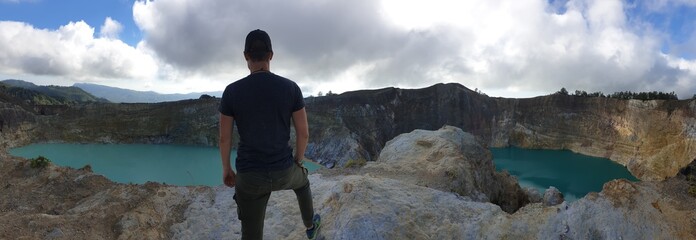 Man standing at the volcano rim and watching the Kelimutu volcanic crater lakes in Moni, Flores,...