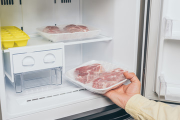 cropped view of man taking out frozen meat from freezer
