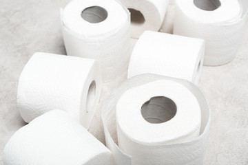 close up view of rolls of toilet paper on grey textured surface