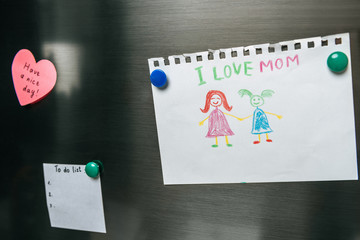close up view of notes and drawing on fridge door