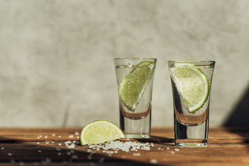 fresh tequila with lime and salt on wooden surface in sunlight