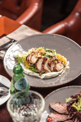 Salad with roasted duck breast and orange with white napkin on wooden table at restaurant
