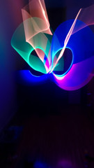 Boy playing in his room in dark with multicolored light stick, creating lighting shapes. Long...