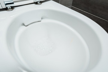 close up view of ceramic clean toilet bowl with foam in modern restroom