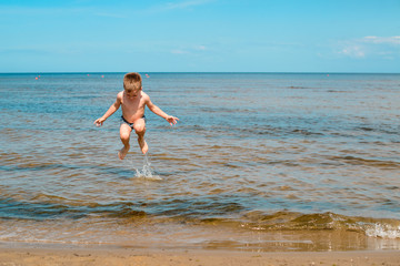 boy swimming in the sea, jumping in the waves of the ocean on the beach