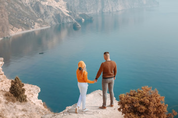 Young men and a woman stand on top of a mountain with panoramic views of the sea bay.