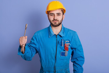 Half length portrait of young bearded manual worker holding wrench tool in one hand and having set...
