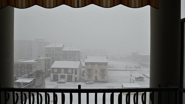 Snowfall on the outskirts of the city: still image from the balcony of a house.From the frame of the railing, pillars and the outdoor curtain show the snow that is covering with a uniform white mantle