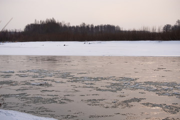 Mountain Russian river in winter. Snow on the shore. Rapid flow of ice water.