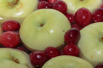 Green apples and red berry in a colander with water. Summer colors in winter.