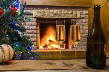 Cozy fireplace. Champagne wine before Christmas tree decorated toys and christmas lights in country cottage.