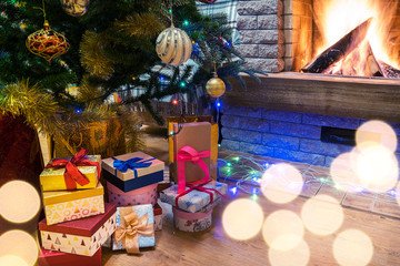 Cozy burning fireplace. Christmas tree decorated toys and christmas lights, gift boxes and candles on floor.