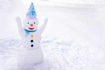 joyful and bright Christmas snowman on the background of fluffy white snow ; copy space