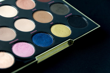 Make-up colorful eyeshadow palettes isolated on black background. View from above. 