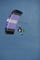 Skydiver under a canopy of a parachute on a background of blue sky close-up.