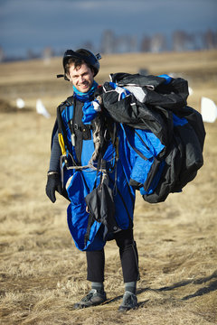 Young skydiver in wingsuit smiles posing for a photo shoot after performing a parachute jump, close-up.