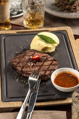 Grilled beef steak with mashed potato on stone board on wooden table at restaurant