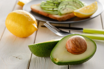 Avocado halves and lemon on wooden table