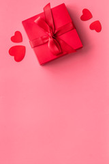 Gift to a sweetheart on Valentine's Day. Red present box near hearts on pink background top-down copy space