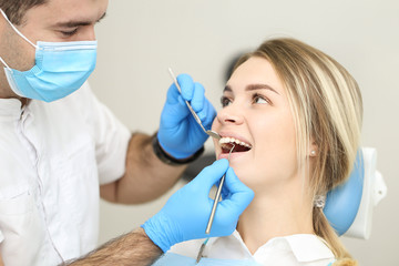 Blond female sits in dentist chair and undergo dentist checkup