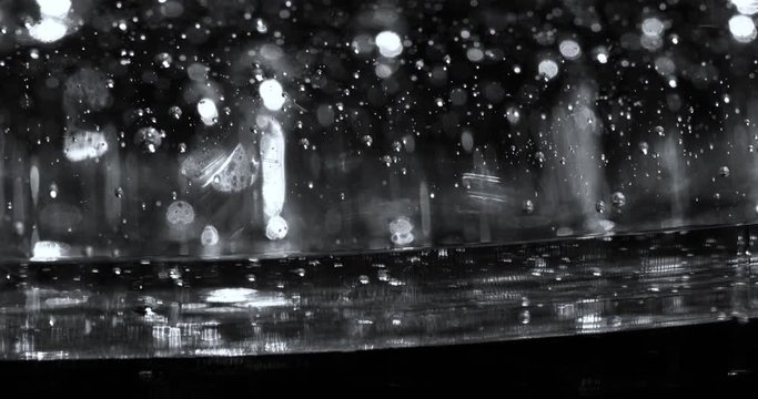 Flow of Transparent Gel Reflecting Specs of Light on Black Surface