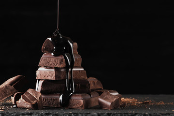 hot chocolate streams  melted chocolate pouring into a piece of chocolate bars   on a dark  table