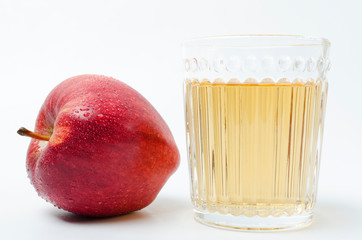 One fresh red apple with water drops and glass of sweet tasty apple juice on the white background