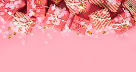 Fototapeta premium Christmas background. Golden gift or present boxes and star confetti on pink top view.