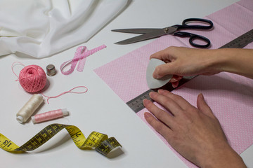 The process of hand sewing with fabric, scissors, accessories for sewing. Hands in chalk draw a line with a ruler on cotton.