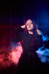 Portrait of chubby teen girl during photoshoot with colored smoke at night and black background