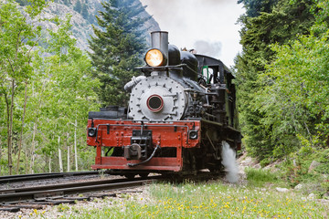 Fototapeta premium Vintage Steam Train Billowing Smoke as it Moves Through the Mountains.