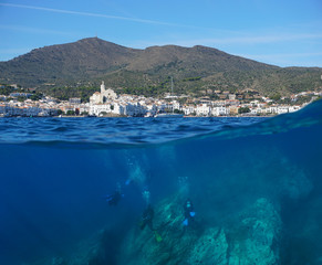 Spain, Cadaques village coastline with scuba divers underwater, Mediterranean sea, split view above and below water surface, Costa Brava, Catalonia