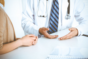 Doctor and patient woman discussing something at the desk in hospital office. Concepts of medical ethics and helping people in medicine