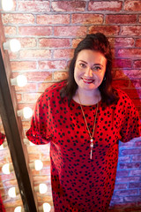 Fat plump charming cute woman with black hair in red beautiful dress in the room with mirrow and...