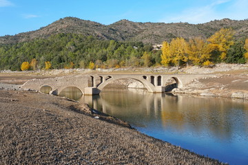 Naklejka premium Spain, an old stone bridge in the reservoir of Boadella with a low water level, Catalonia, Girona province, Alt Emporda