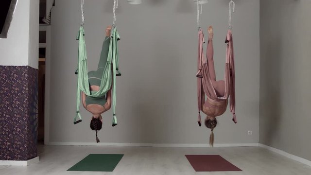 Two aerial yoga female teachers showing elements of a workout