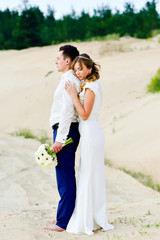 Fototapeta na wymiar Beautiful newlyweds among the sand dunes