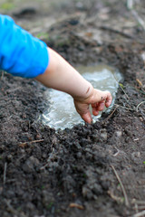 Anonymous child arms and hands playing with mud and water