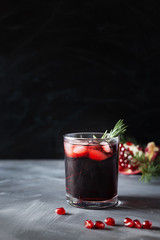 Pomegranate Christmas cocktail with champagne, club soda and rosemary on black table. Xmas drink.