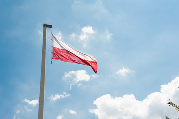 Red and white flag of Poland against blue sky