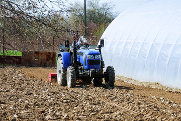 Farmer plows the field. Small tractor with a plow in the field. Cultivation.