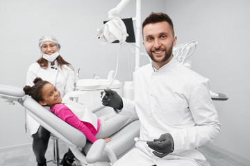 Dentist keeping equipment while child lying on dentist chair
