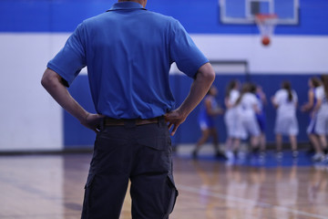 A girls basketball coach watches his defense give up a basket.