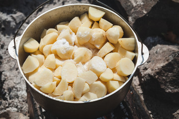Raw peeled potato with salt lay in a round cauldron, close-up