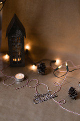 A flat lay of christmas themed objects - fairy lights, bobbles, pine cones and candles and tiny scandinavian houses