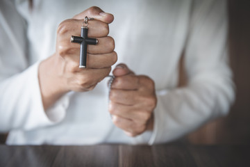 Fototapeta premium A cross in the hands of a young woman blessing on the scriptures from God with the power and power of holiness, which brings luck and the power of religion, faith, worship, Christian thought.
