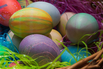 a woven easter basket with colored eggs and plastic grass