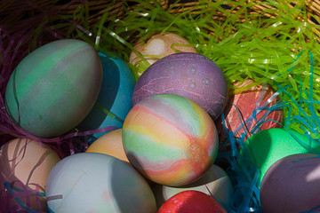 a woven easter basket with colored eggs and plastic grass