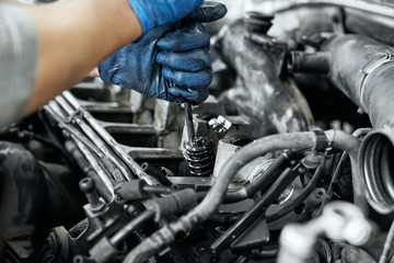 Close up of man's hands tighten bolts in spark plugs