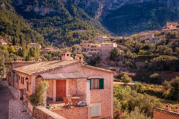 Obraz premium Typical Spanish houses in Valldemossa town, surrounded by mountains and trees, sunny day,, Mallorca, Spain.